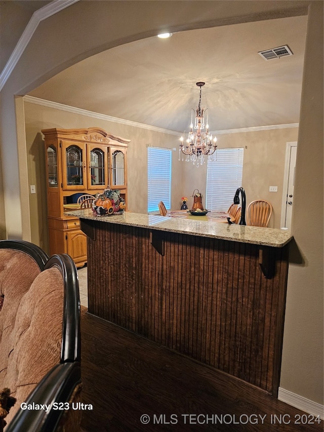 bar with a chandelier, dark hardwood / wood-style floors, pendant lighting, crown molding, and light stone counters