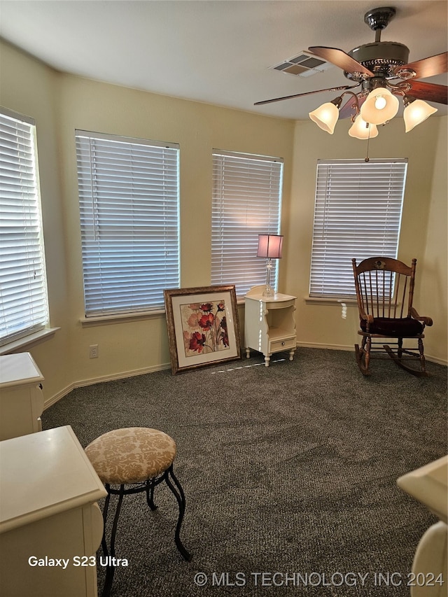 living area with ceiling fan and dark colored carpet