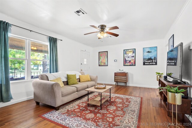 living room featuring ornamental molding, ceiling fan, and wood-type flooring