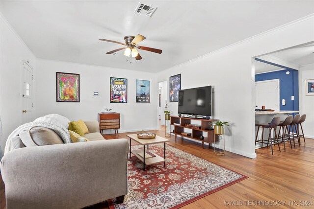 living room with light wood-type flooring, crown molding, and ceiling fan