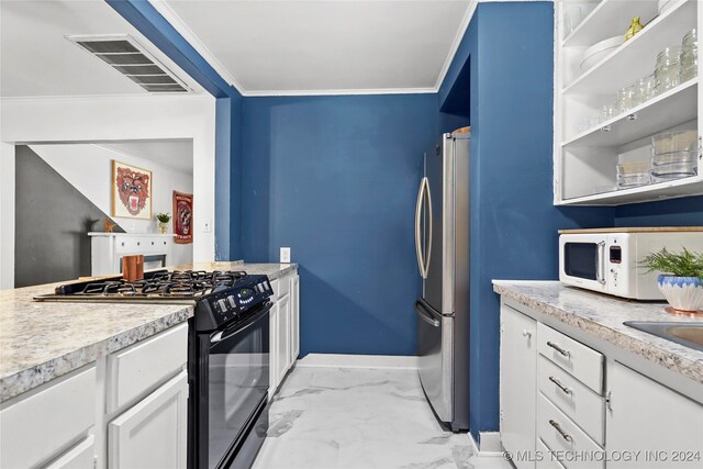 kitchen with black gas range oven, ornamental molding, white cabinets, and stainless steel fridge