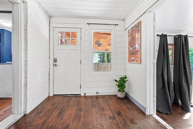 foyer featuring brick wall, crown molding, and dark hardwood / wood-style flooring