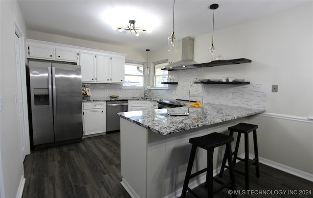 kitchen featuring kitchen peninsula, appliances with stainless steel finishes, white cabinetry, and pendant lighting