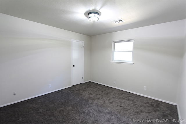 spare room featuring dark carpet