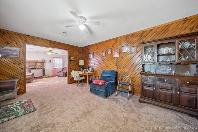 living room with wood walls, light carpet, and ceiling fan