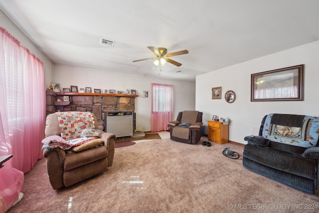 living room with a stone fireplace, carpet floors, and ceiling fan