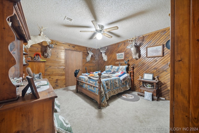 bedroom with carpet, ceiling fan, wood walls, and a textured ceiling