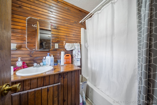 bathroom featuring vanity, wood walls, a textured ceiling, and shower / bathtub combination with curtain