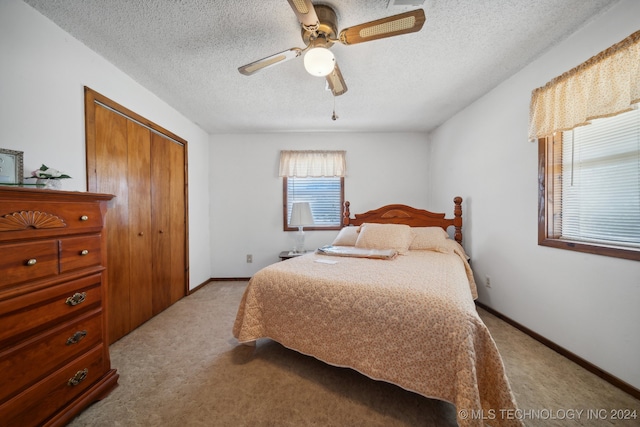 carpeted bedroom with a closet, ceiling fan, and a textured ceiling