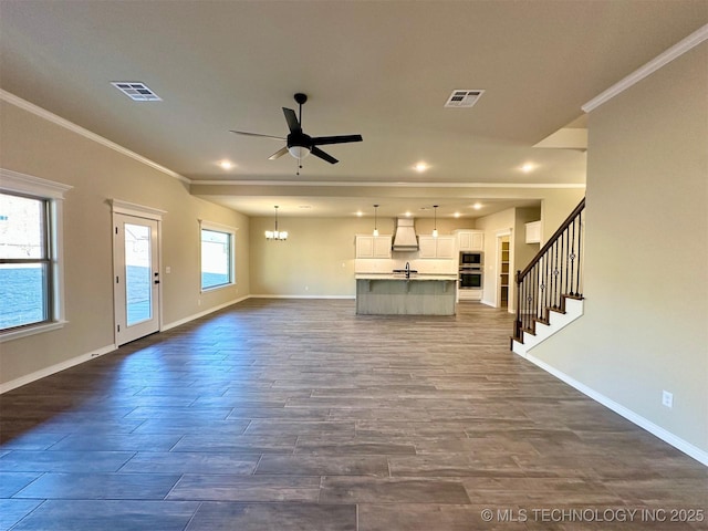 unfurnished living room with ornamental molding and ceiling fan with notable chandelier