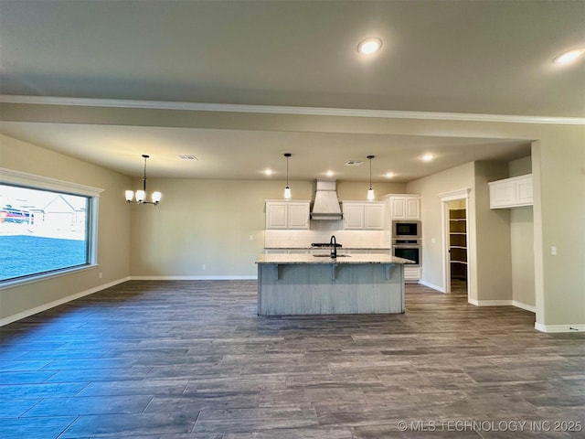 kitchen featuring sink, white cabinetry, a center island with sink, custom range hood, and stainless steel appliances