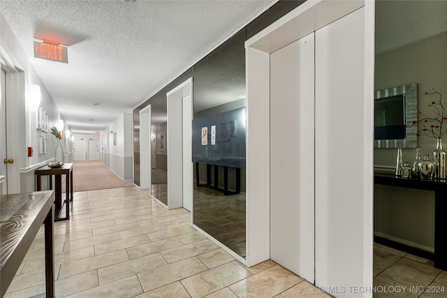 corridor with light tile patterned floors and a textured ceiling