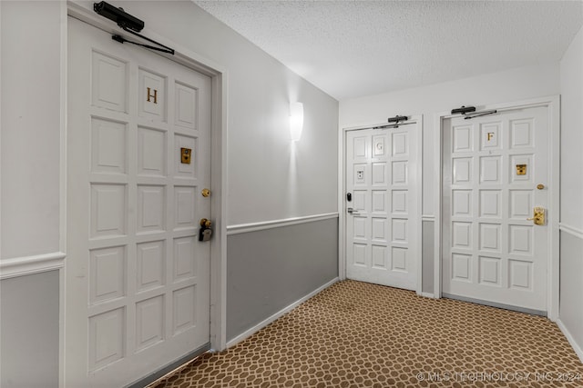 foyer entrance featuring a textured ceiling and carpet