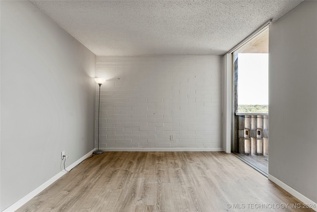 empty room with light wood-type flooring and a textured ceiling