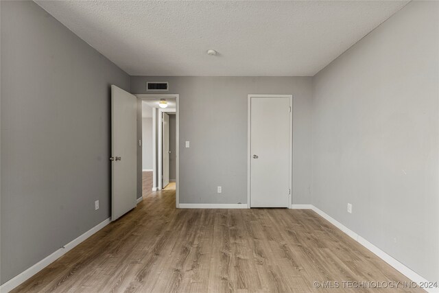 unfurnished bedroom with a textured ceiling and light hardwood / wood-style floors