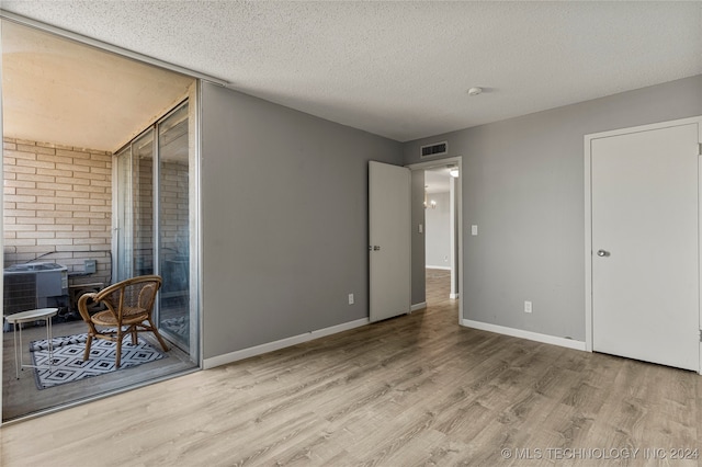 spare room with a textured ceiling, light hardwood / wood-style flooring, and a wood stove