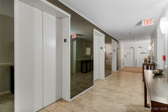 hallway featuring elevator and a textured ceiling