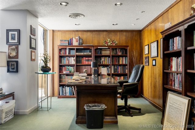 home office with a textured ceiling, wood walls, and carpet flooring