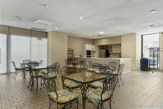 tiled dining space featuring expansive windows and a textured ceiling