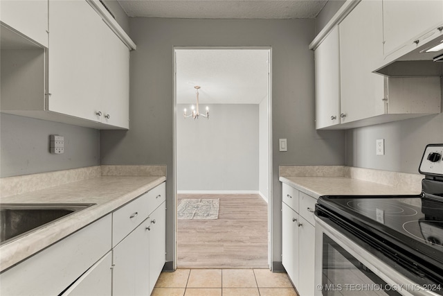 kitchen featuring light hardwood / wood-style flooring, a notable chandelier, white cabinets, and black electric range