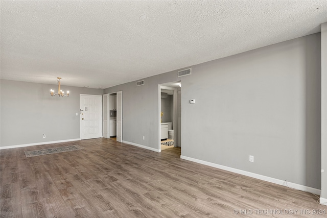 unfurnished living room with wood-type flooring, a notable chandelier, and a textured ceiling