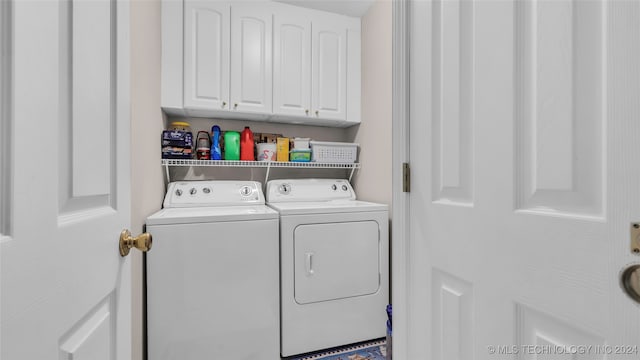 clothes washing area featuring washing machine and clothes dryer and cabinets