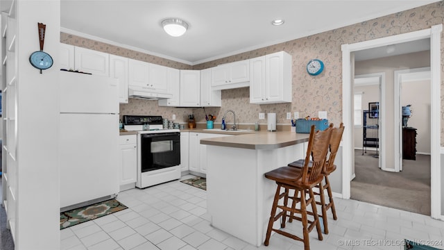 kitchen with crown molding, white appliances, white cabinetry, and a breakfast bar area