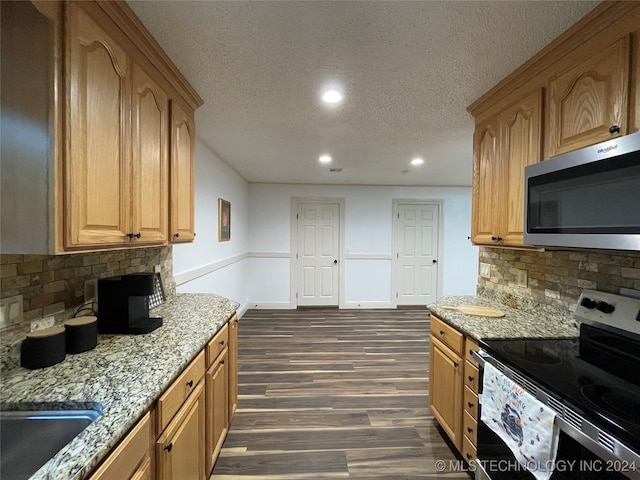 kitchen featuring dark wood-type flooring, backsplash, light stone countertops, appliances with stainless steel finishes, and a textured ceiling