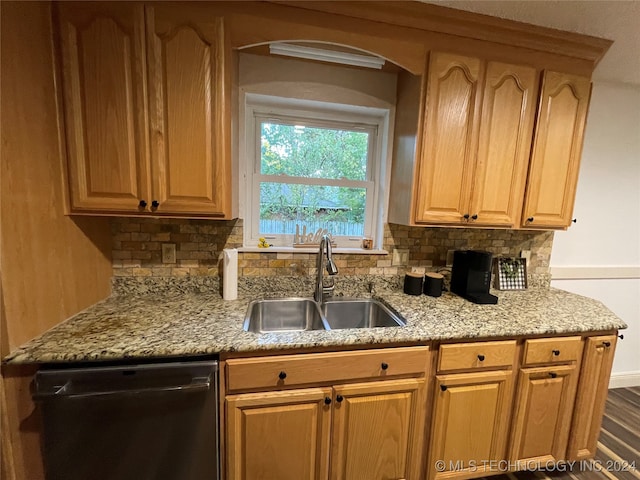 kitchen with black dishwasher, sink, light stone counters, hardwood / wood-style flooring, and decorative backsplash