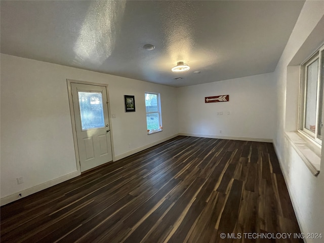 interior space with a textured ceiling and dark hardwood / wood-style floors