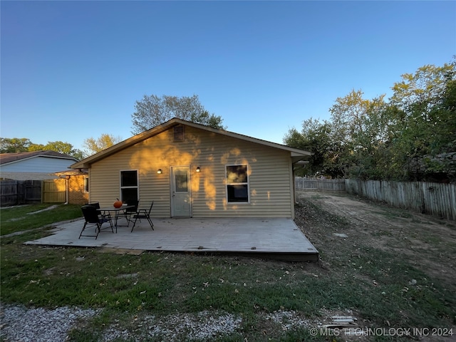 back of property with a wooden deck and a lawn