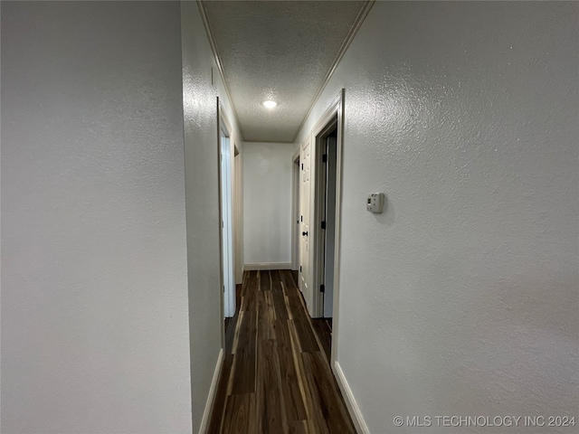 hallway with dark wood-type flooring, crown molding, and a textured ceiling