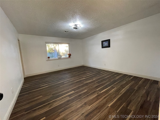 unfurnished room featuring a textured ceiling and dark hardwood / wood-style flooring