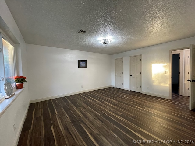 empty room featuring dark wood-type flooring and a textured ceiling