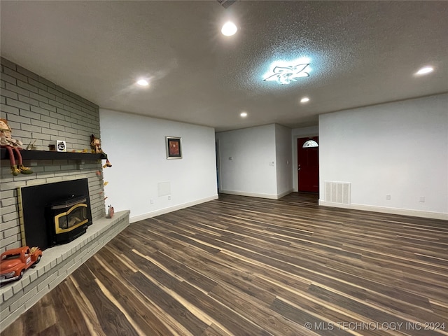 unfurnished living room with a textured ceiling, dark hardwood / wood-style floors, and a wood stove