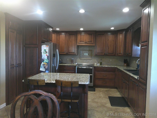 kitchen featuring a kitchen island, sink, stainless steel appliances, light stone countertops, and backsplash