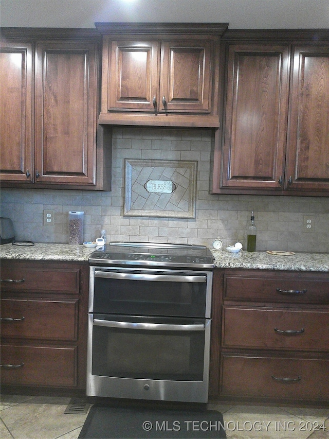 kitchen with tasteful backsplash, dark brown cabinets, light stone counters, and stainless steel electric stove