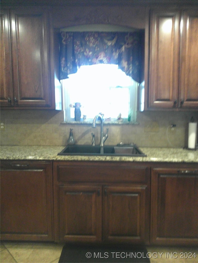 kitchen with sink, light stone counters, and decorative backsplash