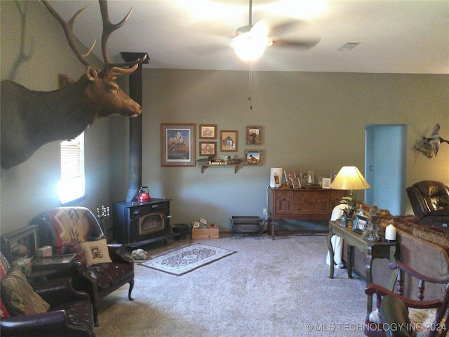 living room with ceiling fan, carpet flooring, and a wood stove