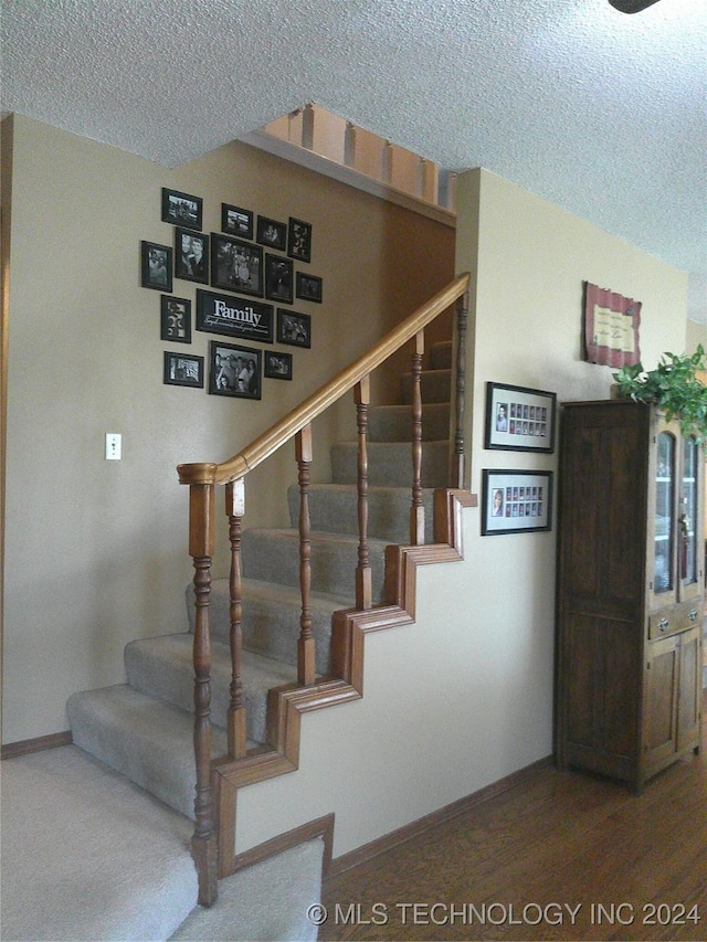 stairway featuring hardwood / wood-style floors and a textured ceiling