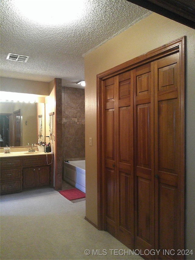 bathroom with independent shower and bath, vanity, and a textured ceiling