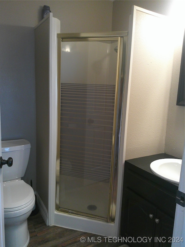 bathroom with hardwood / wood-style floors, toilet, walk in shower, and vanity