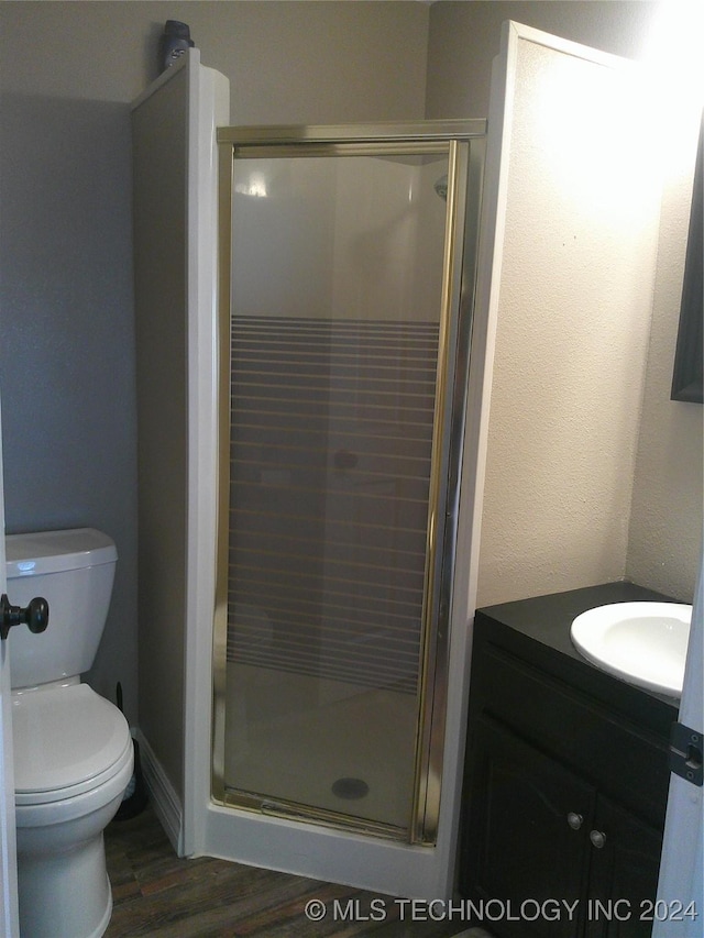 bathroom with an enclosed shower, vanity, hardwood / wood-style flooring, and toilet