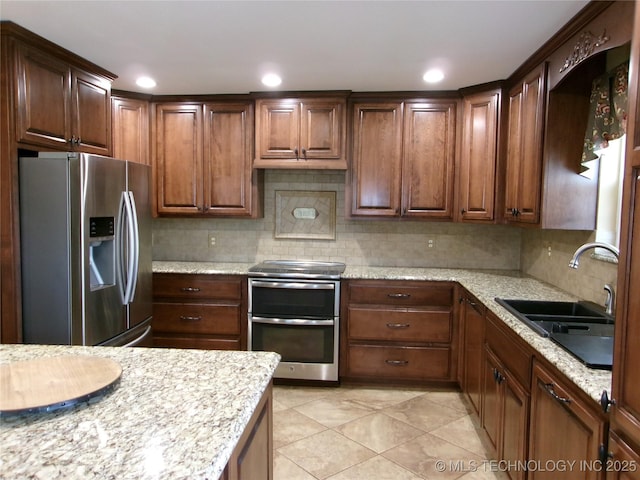 kitchen featuring sink, appliances with stainless steel finishes, light stone counters, tasteful backsplash, and light tile patterned flooring