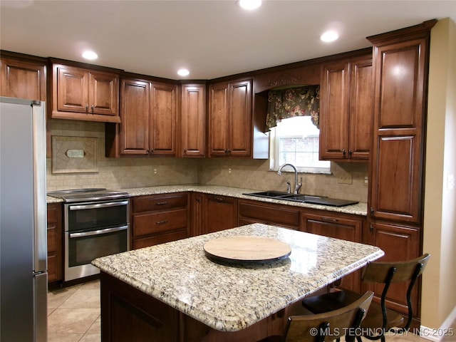 kitchen featuring appliances with stainless steel finishes, sink, a kitchen bar, decorative backsplash, and light stone countertops