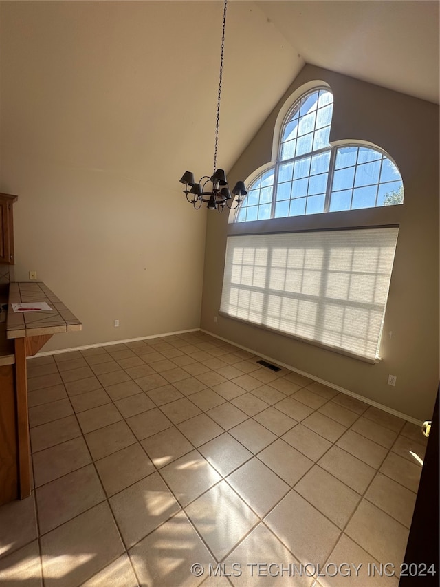 unfurnished dining area with vaulted ceiling, a notable chandelier, and light tile patterned floors