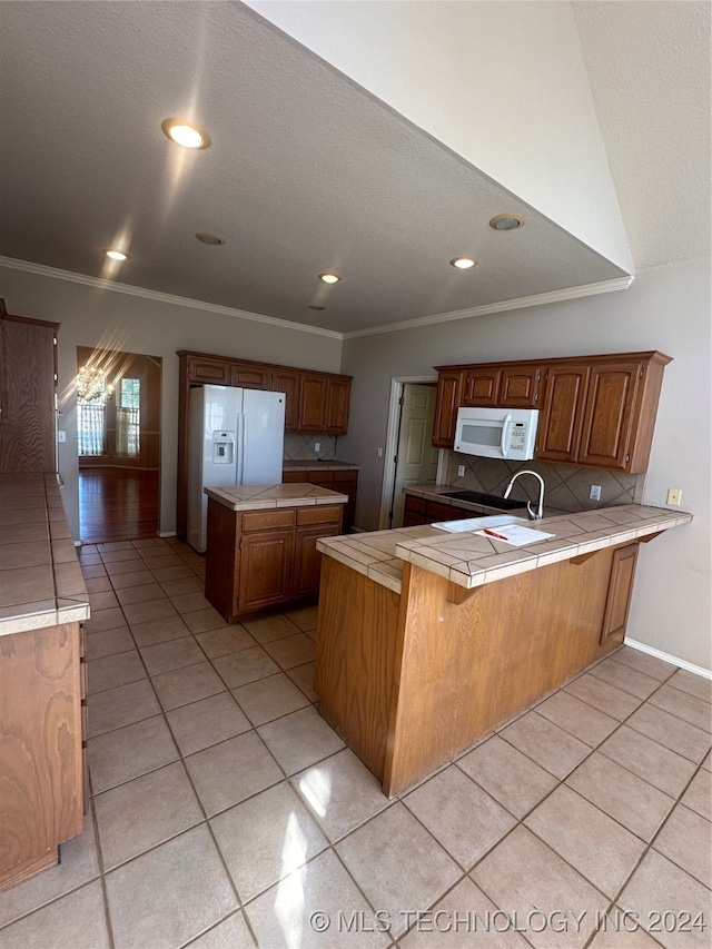 kitchen with white appliances, tile countertops, kitchen peninsula, ornamental molding, and light tile patterned floors