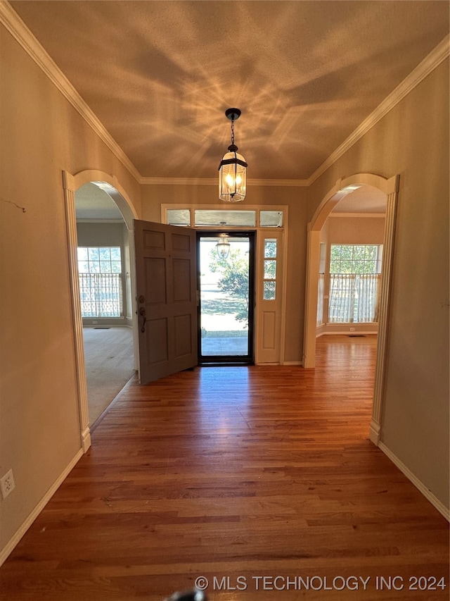 entryway with a notable chandelier, crown molding, and dark hardwood / wood-style flooring