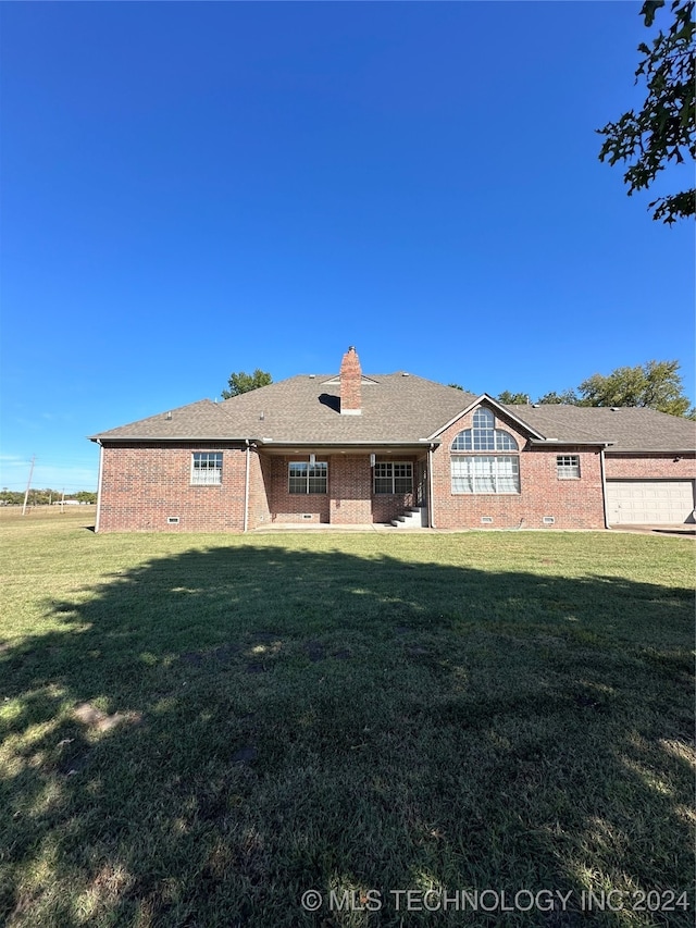 back of property with a lawn and a garage