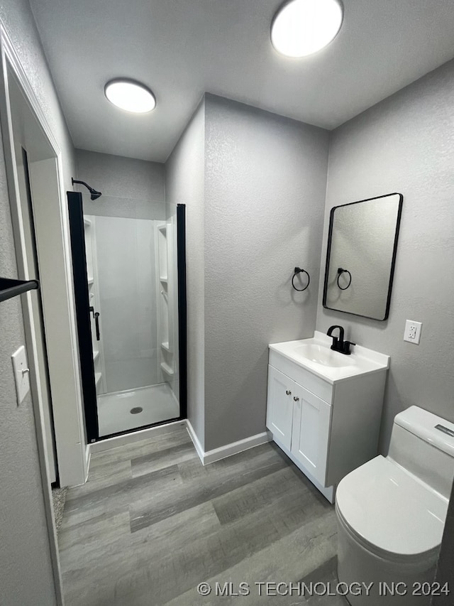 bathroom with a shower, wood-type flooring, vanity, and toilet